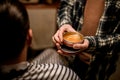round jar with hair gel for styling in hands of male barber.