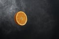 Round juicy fresh orange orange slice on black gradient background