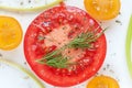 Round juicy slice of red tomato with herbs de Provence, sea salt and slices of yellow tomatoes.