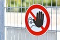 Round `Keep out` warning sign with person holding up hand in red circle at fence protecting construction site Royalty Free Stock Photo