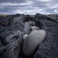 Round lava stones in a fissure in grey vulcanic rock, Hvaleyri beach, Iceland