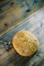 Round loaf of bread lies below on a wooden table. Top view Royalty Free Stock Photo