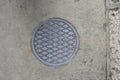 Round manhole cover witj a diamond pattern on the sidewalk Royalty Free Stock Photo