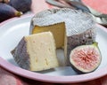 Round mature French Tomme cheese with cutted piece close up