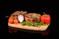 Round meat steak on a wooden board with vegetables Royalty Free Stock Photo