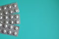 Round medical tablets in three packs, tablets packed in blisters on the left side with copyspace on blue background