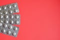 Round medical tablets in three packs, tablets packed in blisters on the left side with copyspace on coral background Royalty Free Stock Photo