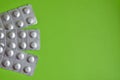 Round medical tablets in three packs, tablets packed in blisters on the left side with copyspace on green background Royalty Free Stock Photo