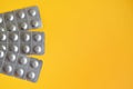 Round medical tablets in three packs, tablets packed in blisters on the left side with copyspace on yellow background Royalty Free Stock Photo