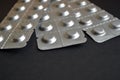 Round medical tablets in three packs, tablets packed in the blisters on the top, with copyspace on black background Royalty Free Stock Photo
