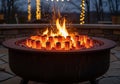 A round metal fire pit filled with artificial ceramic logs and glowing Royalty Free Stock Photo