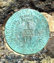 A round metal marker on the mountain of Alander Mountain