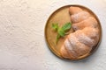 Round metal tray with tasty croissants on light textured background