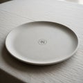 A round, minimalist white plate is centered on a textured tablecloth. The plate feature Royalty Free Stock Photo