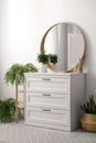 Round mirror and chest of drawers near white wall in room. Modern interior Royalty Free Stock Photo