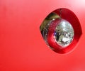 Round mirror disco ball. It is in the red hole, which is part of the red wall. The mirror ball reflects the surrounding area, Royalty Free Stock Photo