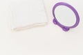 Round mirror with fuchsia frame and white towel on a soft bright white desk