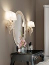 A round mirror with a golden rim on the wall, two sconces on each side, above the dressing table Royalty Free Stock Photo