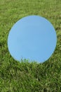 Round mirror on grass reflecting sky on sunny day