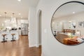 Round mirror reflective the interior of a modern residential home living room and kitchen