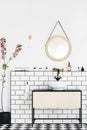 Round mirror on white wall above washbasin in modern bathroom interior with plant. Real photo Royalty Free Stock Photo