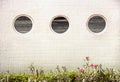 3 round mirror windows in a row on a white tiled building