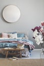 Round mirror in wooden frame on grey wall of elegant bedroom interior with comfortable bed with pastel, blue and pink bedding Royalty Free Stock Photo