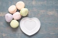 Round multi-colored marshmallows in a pile and a white plate in the shape of a heart on a blue wooden background Royalty Free Stock Photo