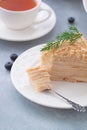 Round multi-layered cake Napoleon with custard, on a light-blue table background. Selective focus. Russian cuisine. Royalty Free Stock Photo