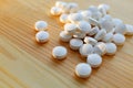 Round natural white vitamin mineral pills lies on wooden table Royalty Free Stock Photo
