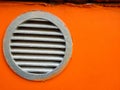 Round new metal ventilation grill on the wall of a building. Background of an orange building. Place for text Royalty Free Stock Photo