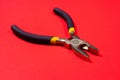 The round nose pliers on the red background of copyspace. For electrician, jeweler and builder. Metal tool for bending wire and