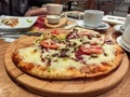 Round pide or Turkish pizza with cheese, sujuk and different types of meat on a wooden tray. selective focus. small focus area Royalty Free Stock Photo