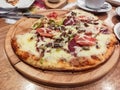 Round pide or Turkish pizza with cheese, sujuk and different types of meat on a wooden tray. selective focus. small focus area Royalty Free Stock Photo