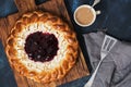 Round pie with cottage cheese and berry jam, coffee with milk, dark background. From above. Royalty Free Stock Photo