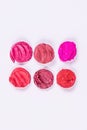 Round pieces of sliced lipstick in two rows on a white background. Colorful lipsticks. Isolated