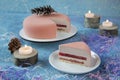 Round pink strawberry Christmas cake and piece of cake with cones surrounded by burning candles and decorations for Christmas is a