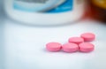 Round pink tablets pill on blurred drug bottle. Vitamins and minerals plus folic acid vitamin E and zinc in drug bottle Royalty Free Stock Photo