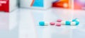 Round pink tablets pill and white-blue capsule pills on blurred background of drug packaging. Painkiller medicine. Drug use Royalty Free Stock Photo