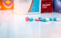 Round pink tablets pill and white-blue capsule pills on blurred background of drug packaging. Painkiller medicine. Drug use Royalty Free Stock Photo