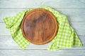 Round pizza board with green checked tablecloth on rustic wooden table .Kitchen, cooking or baking mock up background for design