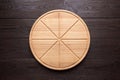 Round pizza cutting board with slice grooves on wooden table Royalty Free Stock Photo