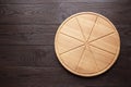 Round pizza cutting board with slice grooves on wooden table top view Royalty Free Stock Photo