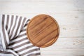 Round pizza cutting board and striped tablecloth on white wooden background. Top view. Copy space and mock up Royalty Free Stock Photo