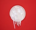 Round plate and stack of plastic forks and spoons on red background Royalty Free Stock Photo