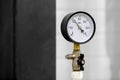 A round pressure gauge in a black case, installed on a pipeline with a valve Royalty Free Stock Photo