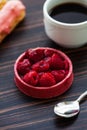 Round raspberry cake decorated with fresh raspberries. In the background, a white mug with coffee and eclairs Royalty Free Stock Photo