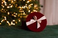 Round red gift box with a bow on the background of Christmas lights with copy space Royalty Free Stock Photo