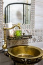 Round retro brass sink and mirror in the interior of the bathroom. Royalty Free Stock Photo