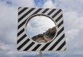 Round road mirror against the cloudy sky